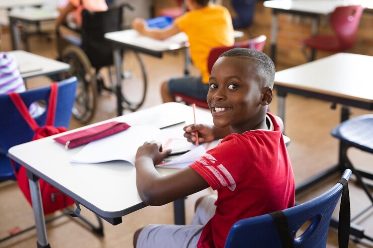 portrait-african-american-boy-smiling-while-sitting-his-desk-class-elementary-school_13339-302355